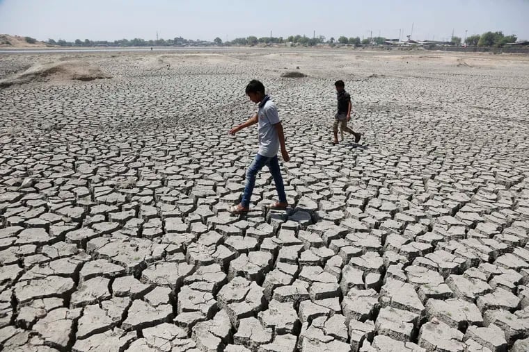 FILE - In this May 14, 2016, file photo, boys on their way to play cricket walk through a dried patch of Chandola Lake in Ahmadabad, India. The decade that just ended was by far the hottest ever measured on Earth, capped off by the second-warmest year on record, NASA and the National Oceanic and Atmospheric Administration reported Wednesday, Jan. 15, 2020. (AP Photo/Ajit Solanki, File)