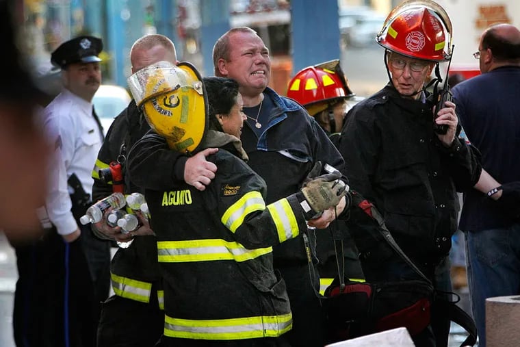 Philadelphia firefighters mourn the deaths of two firefighters during a five-alarm fire at a Kensington warehouse on Monday, April 9, 2012. ( ALEJANDRO A. ALVAREZ / Staff Photographer )