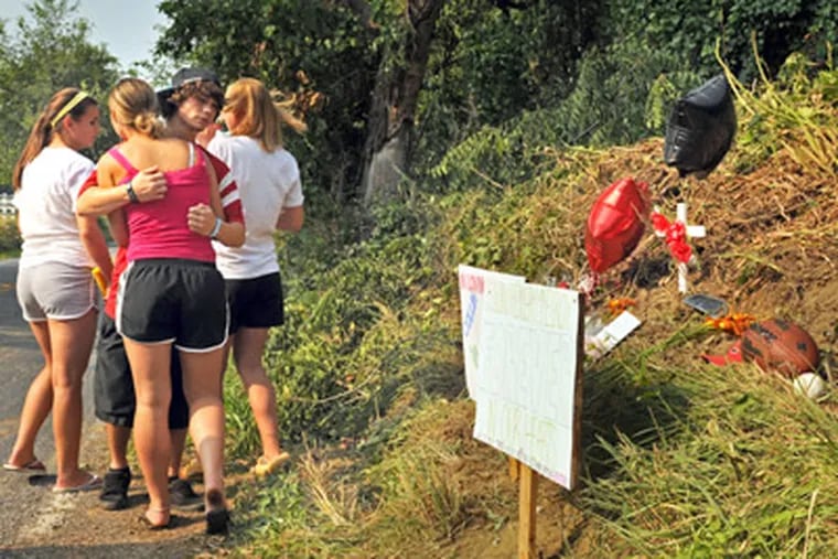 Tyler Wales hugs Brittany Alison (back showing) on Sunday after Alison, Kelsey Brinton (left) and Mandi Geckle (right) brought balloons and signs to a memorial. Four of their classmates died there in a crash. (Tom Gralish / Staff Photographer)