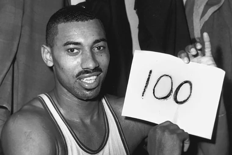 Wilt Chamberlain, of the Philadelphia Warriors, holds a sign reading "100" in the dressing room in Hershey, Pa., March 2, 1962, after he scored 100 points, as the Warriors defeated the New York Knickerbockers.