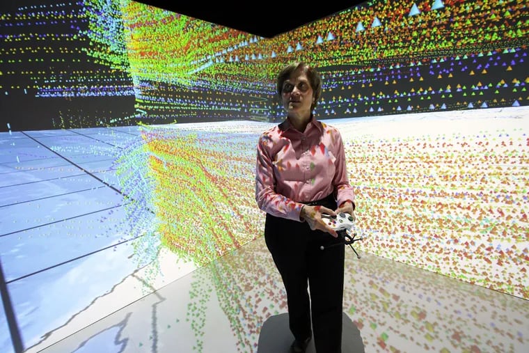 Eileen Rotthoff, lab research assistant, explains the use of a 10-by-10-foot immersive 3-D “cave” with screened walls.