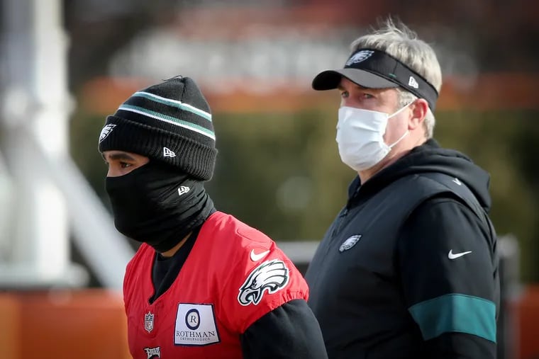 Eagles head coach Doug Pederson (right) watches quarterback Jalen Hurts (left) during practice on Wednesday. The Eagles close out their disappointing season Sunday against Washington.
