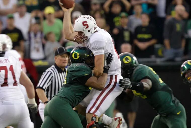 Stanford's quarterback Andrew Luck (12) takes a hit from Oregon's defensive end Kenny Rowe, left and Oregon's defensive end Dion Jordan in the second half of their NCAA college football game Saturday, Oct. 2, 2010, in Eugene, Ore. (Rick Bowmer/AP file)