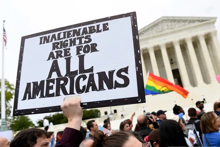 FILE - In this Oct. 8, 2019, file photo, Protesters gather outside the Supreme Court in Washington in October 2019 during arguments in an LGBTG rights case.