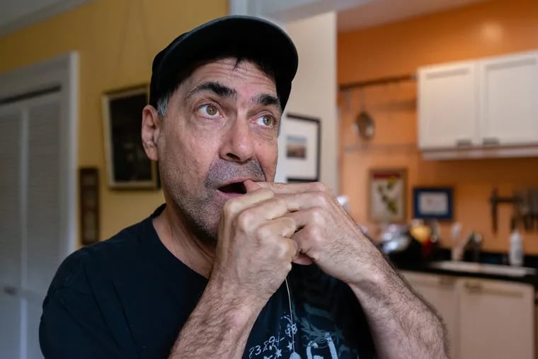 David Tuller flosses his teeth as he walks around his San Francisco home. After he was diagnosed with periodontal disease, Tuller underwent several extractions, titanium implants in his jaw, multiple bone grafts and a series of gum surgeries.