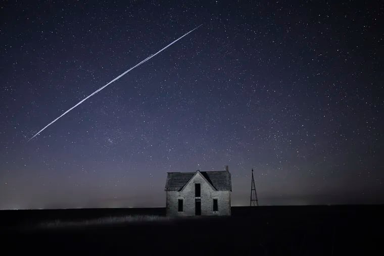 In this photo taken with a long exposure, a string of Elon Musk's SpaceX StarLink satellites passes over an old stone house near Florence, Kan. Some in the Philadelphia area have reported sightings of Musk's internet satellites.