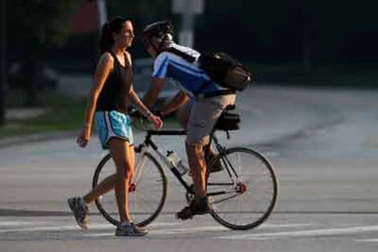 This jogger and cyclist were out by 7 a.m. to exercise along Kelly Drive at Lloyd Hall in Philadelphia today. (Alejandro A. Alvarez / Staff Photographer)