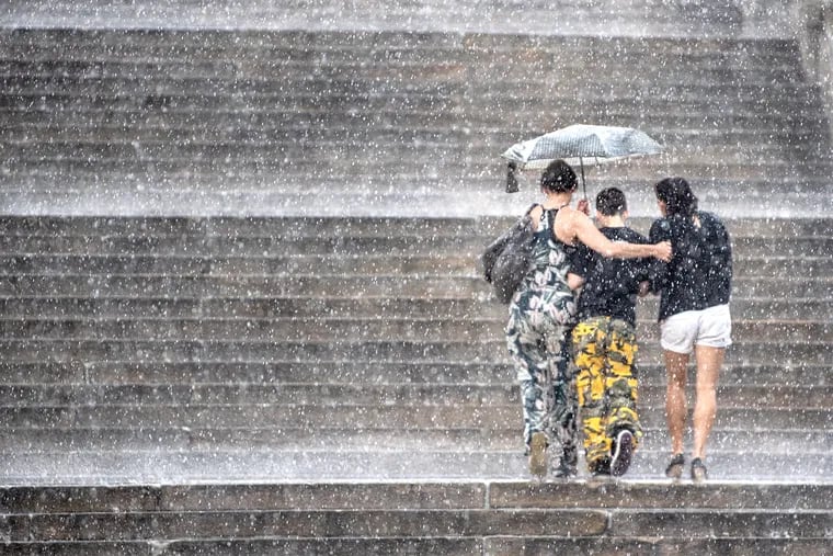 Pedestrians shield from rain with an umbrella on the steps of the Philadelphia Museum of Art during the summer. Would they vote if it rained like this on Tuesday?