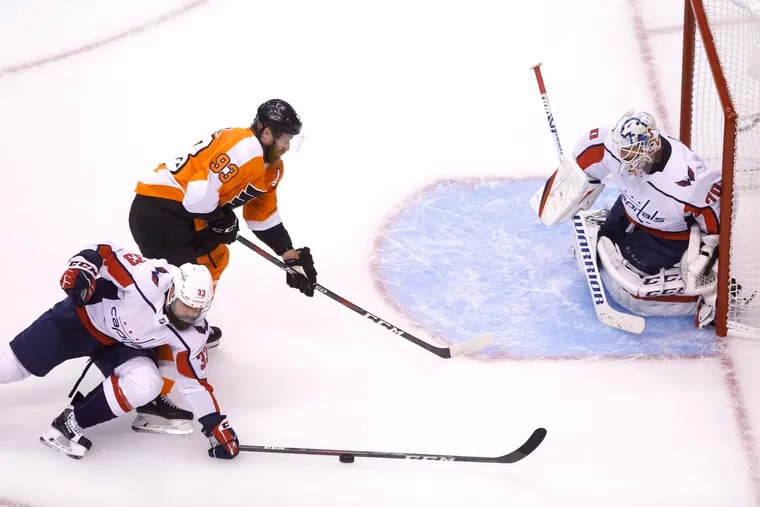 Capitals defenseman Radko Gudas stops the puck in front of  Flyers right winger Jake Voracek as Washington goaltender Braden Holtby holds his ground in a round-robin game.