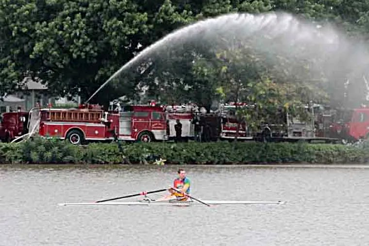 Rowers on the Cooper River near the stream of water from a firetrucks at the Antique Fire Apparatus Association muster at the Cooper River Park, Cherry Hill, August 3, 2013.  ( DAVID M WARREN / Staff Photographer )