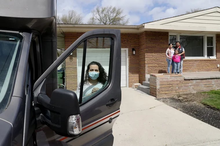 Ana Almonte (left), an ICU nurse, stands for a portrait with the RV she is temporarily living in so she can distance from her family outside their home in Cherry Hill, N.J., on Friday, April 10, 2020. Behind (from left) are her daughters, Lia, 17, and Milania, 6, and her husband, Joshua.