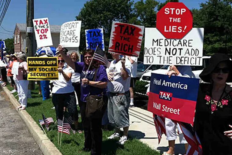 Demonstrators line a street outside U.S. Rep. Jon Runyan's office in Mount Laurel. People urged action to end the standoff over the U.S. debt ceiling. (JOSHUA ADAM HICKS / Staff)