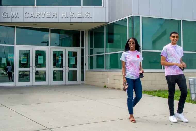 George Washington Carver High School of Engineering and Science seniors Amoya Donaldson (left) and Caleb Autry outside the school. Carver launched its own record label during the pandemic — with students filling every role, from talent to executive producers. Two alums in the business helped get the project off the ground, and students say it provided a bright spot in a tough year, as well as giving them high-level experience in project and music management.
