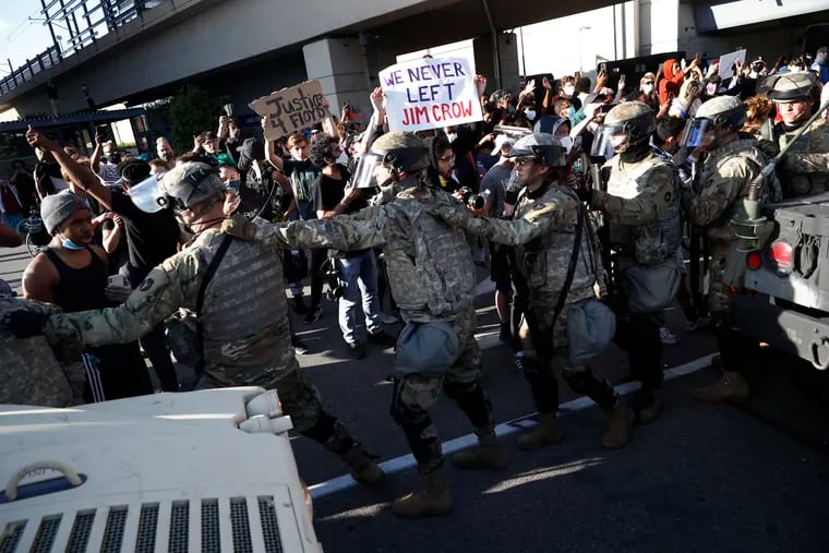 Minnesota National Guard walk past protesters Friday, May 29, 2020, in Minneapolis. Protests continued following the death of George Floyd, who died after being restrained by Minneapolis police officers on Memorial Day.