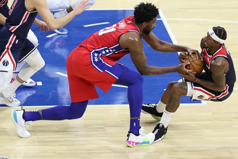Joel Embiid, left, of the SIxers and Bradley Beal of the Wizards battle for a loose ball.