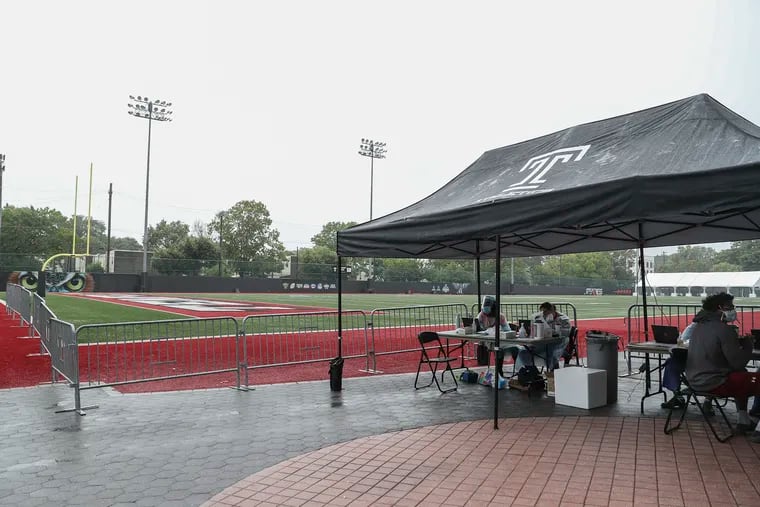 Temple health-care workers setting up a tent to administer coronavirus tests to  members of the Temple football team outside of Edberg-Olson Hall on June 18.