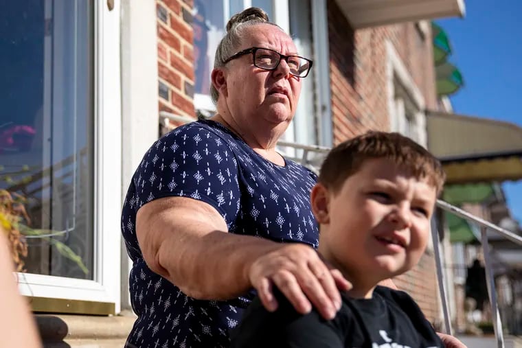 Mary Munizza, 62, sits on her front steps on Hegerman Street in Tacony with grandson Kyle, 7, on Tuesday, Oct. 15, 2019. On Monday night, police responded to the block after another resident fatally shot her two young daughters and their father in their home, police said.