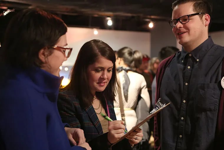 Anna Stormer signs a campaign petition while Nicole McDonald (left) and Chad Hoffmann talk at the pitch party. STEPHANIE AARONSON / Staff Photographer
