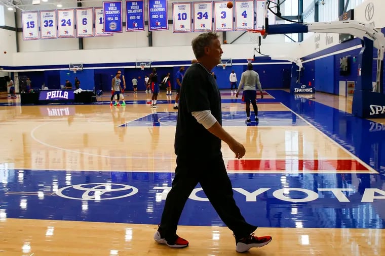 Sixers coach Brett Brown walks to meet the media after a practice at the team's training complex in Camden.