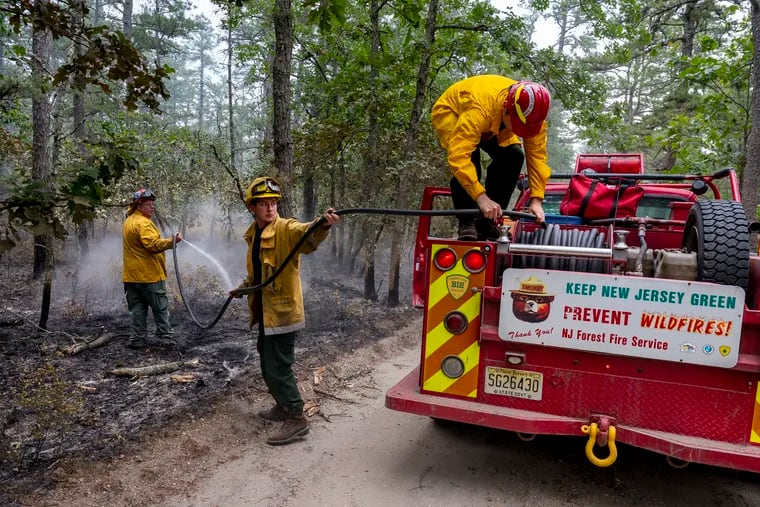 Last week, a fire at Wharton State Forest consumed about 13,500 acres, the largest wildfire in the state since 2007. Firefighters Larry Rosenberg (from left), William Zazenski, and Robbie Knapp, hose down hot areas that remained on June 21 near the Batsto Village historic site.