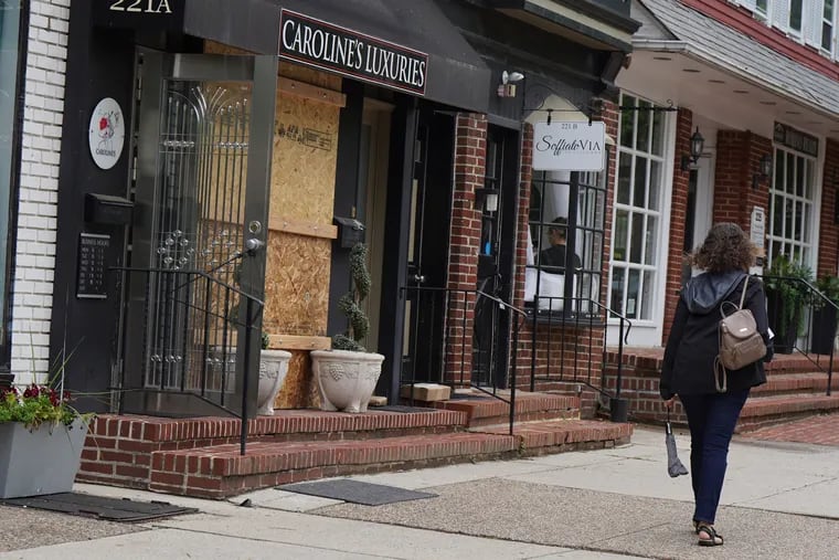 A window that was broken during a robbery is boarded up at Caroline's Luxuries in Haddonfield on Thursday.