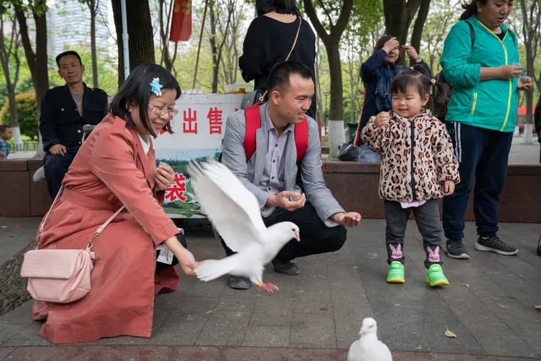 Zeng Yulin (left) with husband Zhou Dongyuan and daughter Zhang Yuewei feed pigeons in a park in Wuhan, China, last month.