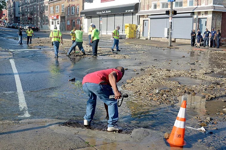 Water Department workers clear drains and cut off water at 52nd Street & Wyalusing Avenue June 14, 2015, near where a 36-inch water main burst in the pre-dawn hours.