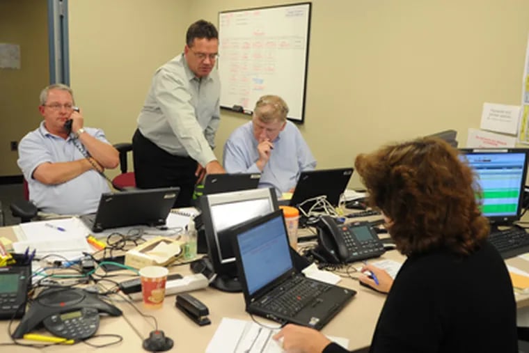 From left, Phil Eastman, John McDonald and John Golden manage PECO teams working in the field to restore power inside PECO's Emergency Operations Center in Plymouth Meeting on Monday. (Sarah J. Glover / Staff Photographer)