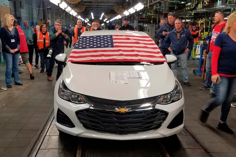 An American flag drapes the hood of the last Chevrolet Cruze as it comes off the assembly line at a General Motors plant where 1,700 hourly positions are being eliminated perhaps for good, on Wednesday, March 6, 2019, in Lordstown, Ohio. The factory near Youngstown is the first of five North American auto plants that GM plans to shut down by next year. (Tim O'Hara via AP)