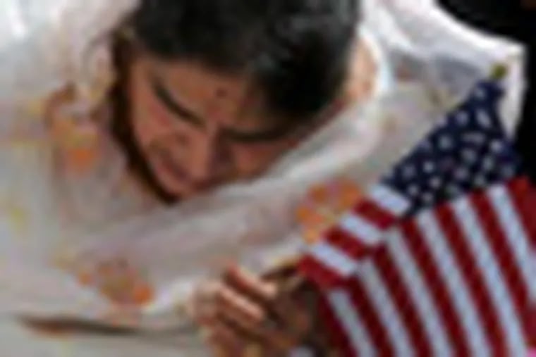 Rupinder Kaur Rehal, member of the Blue Mountain Gurdwara, a Sikh temple in Bethel, holds an American flag as she lights candles during a memorial service for the victims of the August 5th shooting at the Sikh temple in Wisconsin, in Bethel, Pa., Sunday, Aug. 12, 2012. (AP Photo/The Republican-Herald, David McKeown)