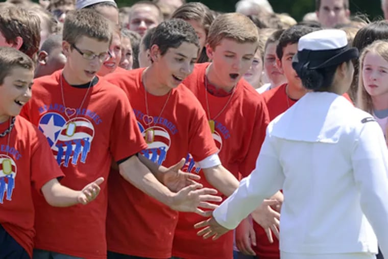Students slap hands with Navy Petty Officer Jin Choe at William Allen Middle School in Moorestown. The school formed a living heart design for the Wounded Warrior Project. (TOM GRALISH / Staff Photographer)