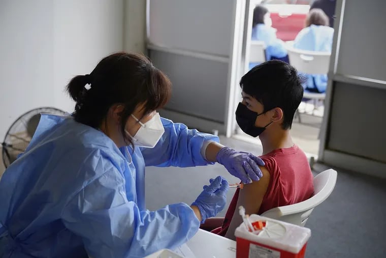 Nurse Hyun Lee (left) administers a COVID-19 vaccine to Stephen Zeng, 15, of Northeast Philadelphia during a pop-up vaccination clinic at the H Mart shopping plaza in June. Pennsylvania is making new grants available to groups working to improve vaccinations in their communities.