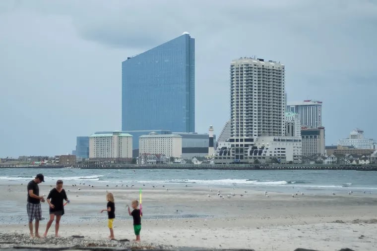 With the Revel as a background, Eric Pratali, of Chicago, and his family hunt for sea shells in Brigantine. ( ED HILLE / staff photographer )