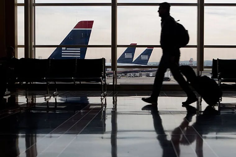 The silhouette of a traveler is seen walking past US Airways Group Inc. planes parked on the tarmac at Ronald Reagan National Airport in Washington, D.C., U.S., on Friday, Nov. 15, 2013. The U.S. settlement allowing the merger of American Airlines parent AMR Corp. and US Airways Group Inc. to go through will open the door to more low-cost carriers at Washington's Ronald Reagan National Airport. (Andrew Harrer/Bloomberg)