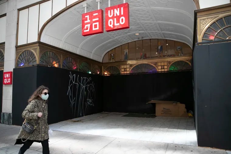A pedestrian walks by a boarded-up Uniqlo store at 16th and Chestnut Streets in Center City Philadelphia last week.