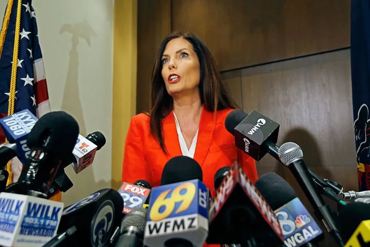 Surrounded by microphones, Pennsylvania Attorney General Kathleen G. Kane announces on Tuesday that she would not be seeking re-election as the state's Attorney General.