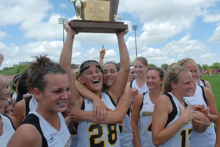 Moorestown's Alyssa Ogle holds the championship trophy while getting a hug from Nicole Laitner. Jenna Hildeband is at left, and Haleigh Dalmass and Katrina Martinelli (17) are right.