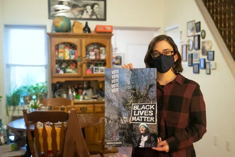 Kait Renna poses for a portrait inside her home in South Philadelphia while holding a voting sign on Thursday, Oct. 29, 2020. People are experiencing anticipatory anxiety before the election, affecting their mental health.
