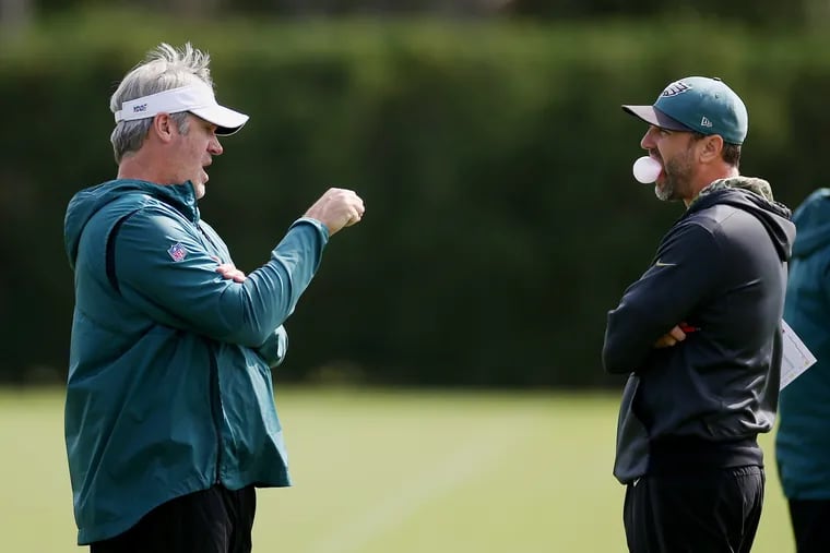 Eagles coach Doug Pederson (left) talking with offensive coordinator Mike Groh during practice at the NovaCare Complex in September.