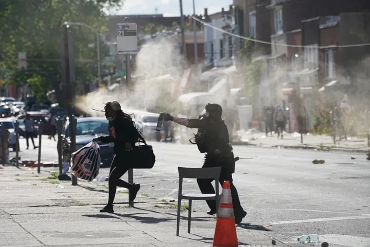 A person runs from a police officer spraying a chemical on 52nd Street in Philadelphia on Sunday, May 31, 2020.