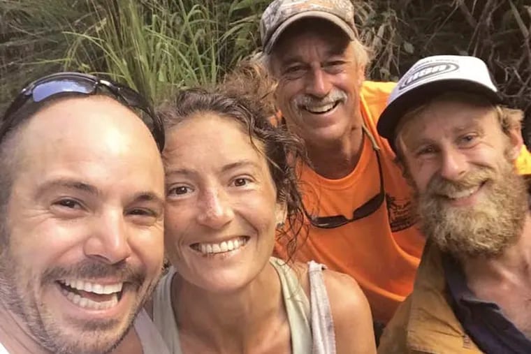 In this Friday, May 24, 2019, photo provided by Troy Jeffrey Helmer, resident Amanda Eller, second from left, poses for a photo after being found by searchers, Javier Cantellops, far left, Helmer and Chris Berquist above the Kailua reservoir in East Maui, Hawaii, on Friday afternoon. The men spotted Eller from a helicopter and went down to retrieve her. She was taken to the hospital and was in good spirits, her family said. Eller had been missing since May 8. (Troy Jeffrey Helmer via AP)