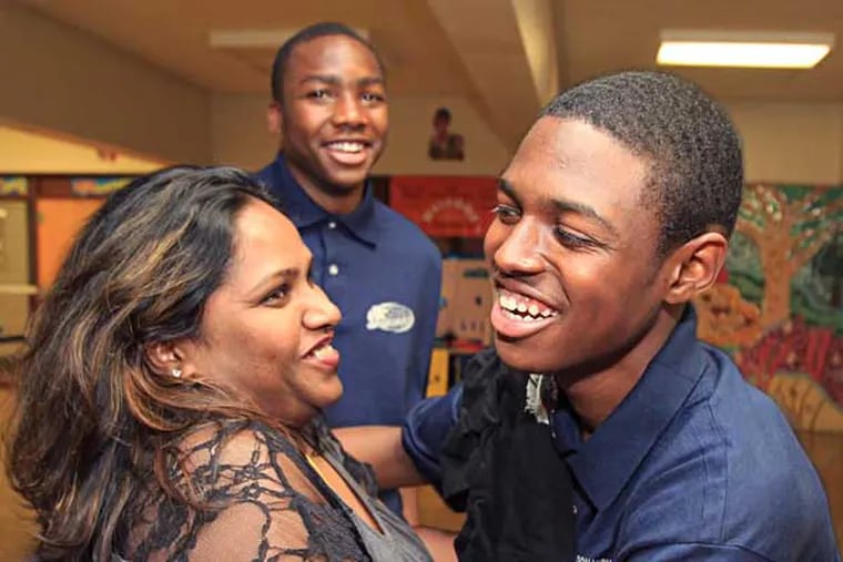 Isaiah Palmer, right, is given a congratulatory hug by Principal Rennu Teli-Johnson, left, as Michael Eugene, center, looks on. Palmer and Eugene, two honor students at Motivational High School, ran into a burning building on their way to school Tuesday morning and saved a sleeping boy. ( CHARLES FOX / Staff Photographer )