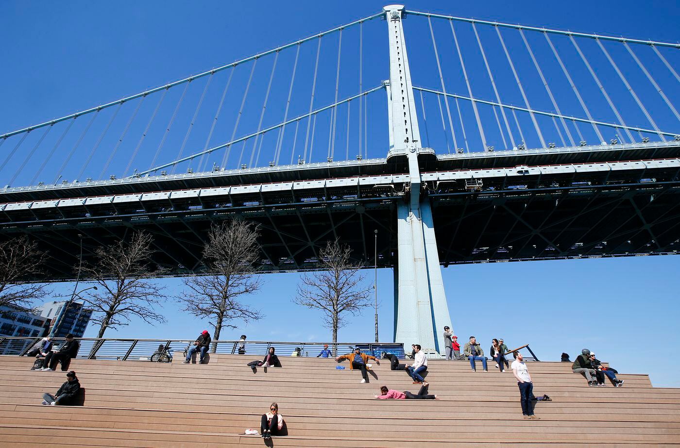 Pedestrians sit on the Race Street Pier below the Ben Franklin Bridge on Saturday, March 21, 2020.
