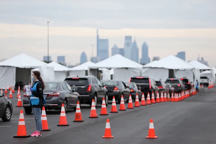 Philadelphia Medical Reserve Corps volunteer Emma Ewing, a sophomore at Temple University, directs cars at the city's coronavirus testing site next to Citizens Bank Park.