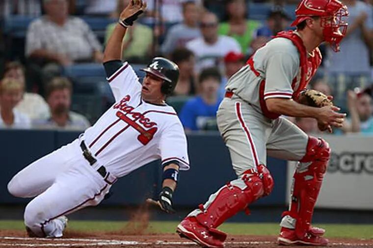 Atlanta's Martin Prado (left) scored three runs and batted in two more against the Phillies. (John Bazemore/AP)