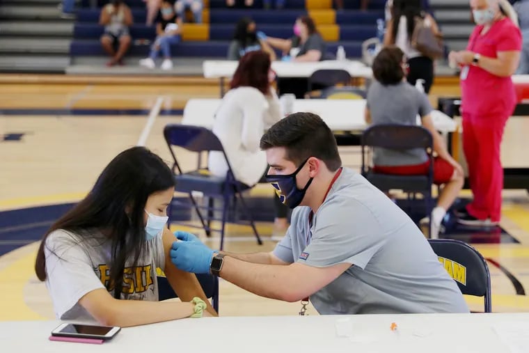 Nurse Timothy Aungst puts a bandage on Gaby Fernandez (left), 15, after administering her first dose of the Pfizer COVID-19 vaccine during a vaccination clinic for children 12 and older at Cheltenham High School in Wyncote, Pa., on Wednesday, May 19, 2021.
