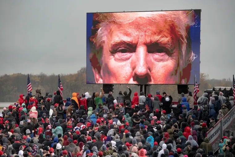 Supporters of President Donald Trump watch a video screen showing his face during a campaign event on Tuesday, Oct. 27, 2020, in Lansing, Mich.