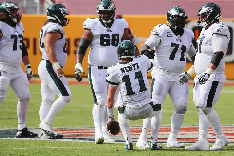 Eagles quarterback Carson Wentz (center) gets a hand up from Eagles offensive guard Jason Peters after being sack on 4th down in the 3rd quarter.