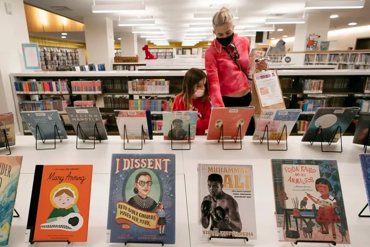 Zoe Slavin and her mother, Julie, browse for books in the children's section of the Stavros Niarchos Foundation Library in New York. New York City's public libraries will no longer charge late fees and will waive existing fines for overdue books and other materials, city officials announced Tuesday.