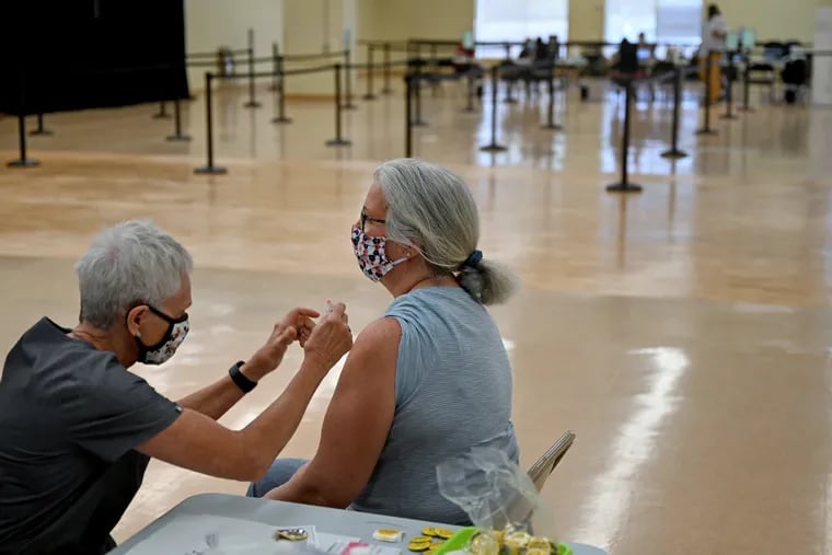 Mary Lou Hardman, 60, of Huntington Valley receives her her vaccine from nurse Anita Crielly (left) at a Montgomery County vaccination clinic in July.